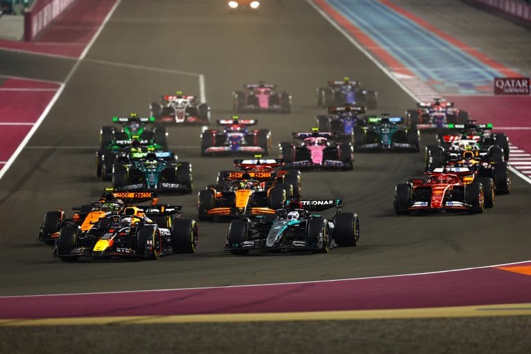 F1 cars racing under Qatar Grand Prix lights in hot conditions